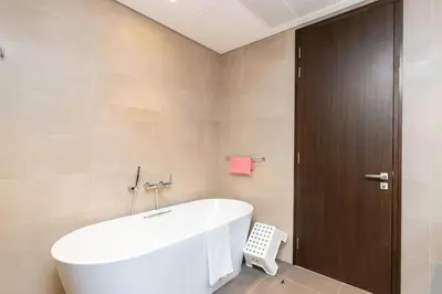 a bathroom with a white tub and a brown door at CitiHome Refined 1BR Jumeirah Living Marina Gate in Dubai