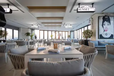 a restaurant with white tables and chairs and windows at Top Amenities, Luxury 2BR, 5 min. to Burj Khalifa in Dubai