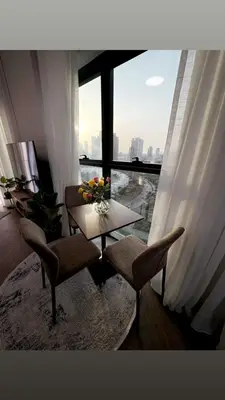 a living room with a table and chairs and a large window at Ruby home in Dubai