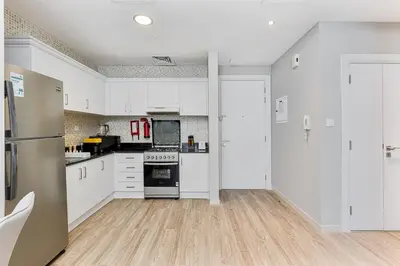 an empty kitchen with white cabinets and appliances at Modern 1BR Unit Close to Canal Walk & Burj Khalifa in Dubai