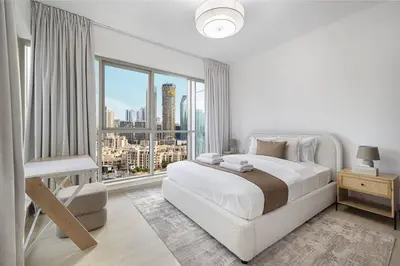 a white bedroom with a large bed and a large window at Boulevard Chic Modern 2BR with Iconic Street Views in Dubai