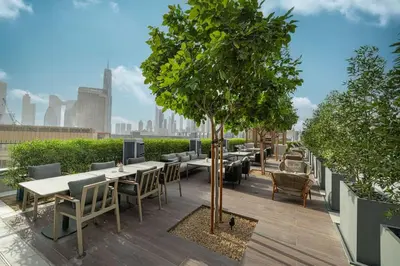 a patio with tables and chairs and a tree on a roof at Heart of Downtown Stylish 2BR at Vida Dubai Mall in Dubai