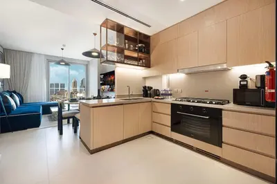 a kitchen with wooden cabinets and a blue couch at Downtown Living Massive 4BR at Vida Dubai Mall in Dubai