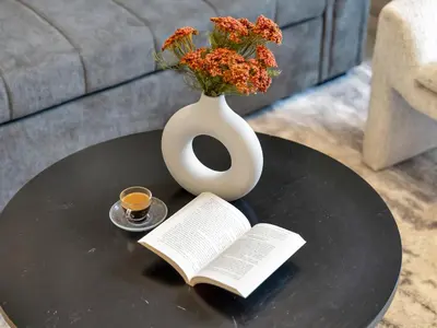 a table with a vase and a book and a cup of coffee at Royal Vista - 1BR with Darts Wall at Belgravia Square JVC in Dubai