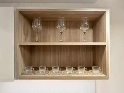 a row of glasses and wine glasses on a shelf at Royal Vista - 1BR with Darts Wall at Belgravia Square JVC in Dubai