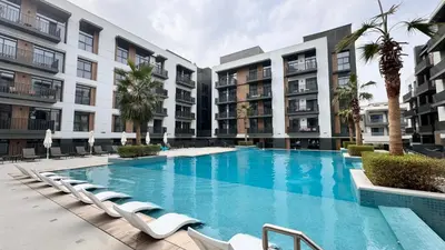 a swimming pool with lounge chairs in front of buildings at Royal Vista - 1BR with Darts Wall at Belgravia Square JVC in Dubai
