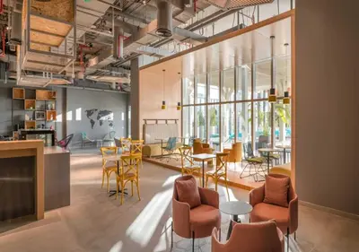 a room with tables and chairs and windows at Elite Studio with Kitchen in Novotel JVT in Dubai