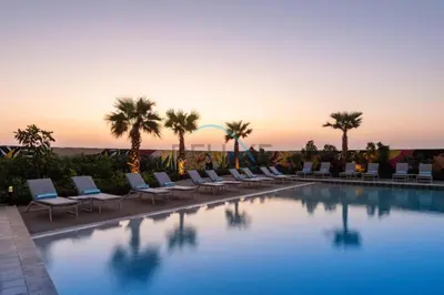 a pool with chairs and palm trees and the sunset at Near Safa Park, Offering Easy Access to Downtown Dubai, Jumeirah Beach and Kite Beach - Aykon City 2 Tower C, Business Bay by Deluxe Holiday Homes in Dubai