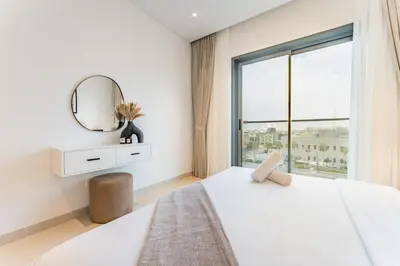 a bedroom with a white bed and a mirror at Just Moments from Coca-Cola Arena and Metro 1BR, Surrounded by a Vibrant Array of Retail and Dining Outlets, Viridian, Al Wasl by Deluxe Holiday Homes in Dubai