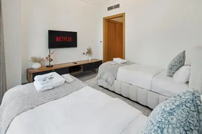 two beds in a room with a tv on the wall at Luxury 4BR Apartment Burj Khalifa & Mall Views in Dubai