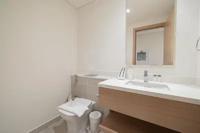 a bathroom with a sink and a toilet and a mirror at 3 Bedroom Apartment with Full Skyline Views In Creek Harbour in Dubai