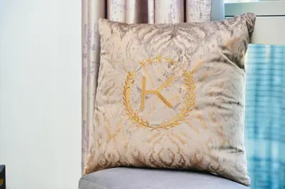 a pillow with a k on it sitting on a chair at ROME x DXB with Full Burj and Fountain View in Downtown Dubai in Dubai