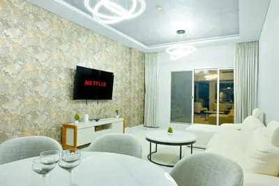 a living room with chairs and a tv on a wall at Luxestay Holiday Homes in Dubai