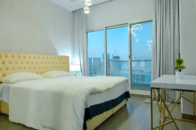 a bedroom with a bed and a large window at Luxestay Holiday Homes in Dubai
