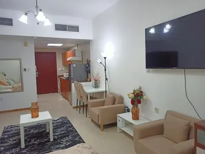 a living room with a couch and a tv on a wall at Dubai Marina Studio in Dubai