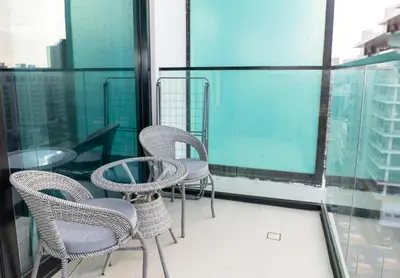 a balcony with chairs and tables on a building at Modern Studio Apartment - Binghatti Azure 633 in Dubai