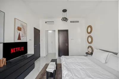 a white bedroom with a bed and a tv at Apartment-Private Bathroom in Dubai