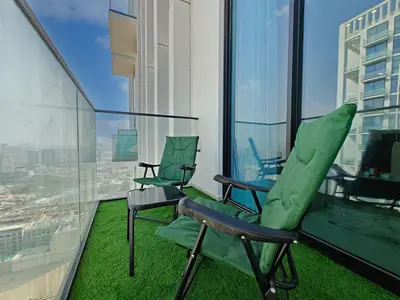 two chairs on a balcony with a view of a city at Brand New High Floor 1 BR with city view, pool and gym in Dubai