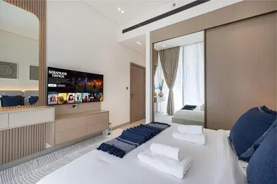 a bedroom with a large white bed with blue pillows at Luxury Binghatti Phantom Suites By Hostiva in Dubai