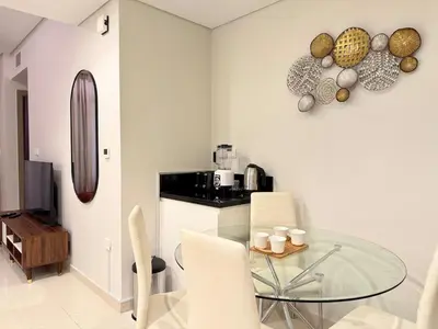 a dining room with a glass table and white chairs at Cozy 2BHK - Sea View in Dubai