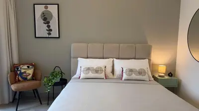 a bedroom with a large bed and a chair at Stylish Studio Apartment in Peninsula 1 in Dubai