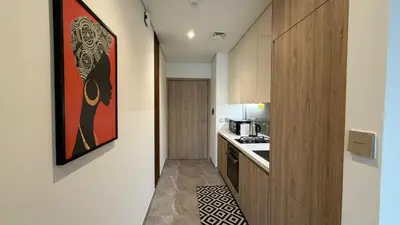a small kitchen with a painting on the wall at Stylish Studio Apartment in Peninsula 1 in Dubai