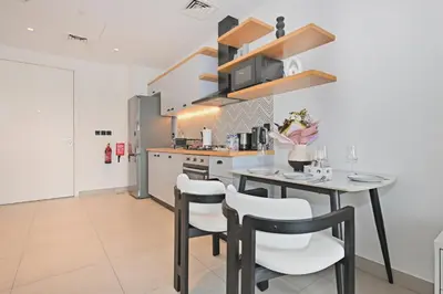 a kitchen with a table and chairs in a room at Socio Tower Apt - Parking, Balcony&Pool - by Rentujemy in Dubai