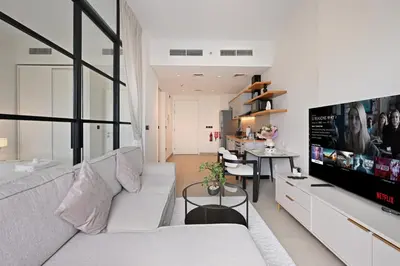 a living room with a white couch and a tv at Socio Tower Apt - Parking, Balcony&Pool - by Rentujemy in Dubai