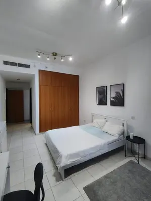 a white bedroom with a bed and a wooden door at Spacious Master Bedroom with Balcony Horizon Tower, Dubai Marina in Dubai