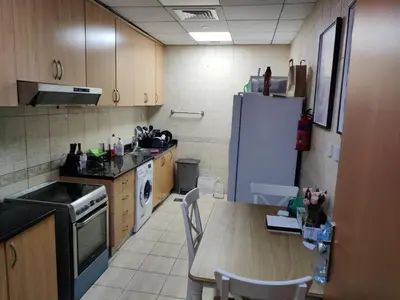 a kitchen with a table and a white refrigerator at Spacious Master Bedroom with Balcony Horizon Tower, Dubai Marina in Dubai