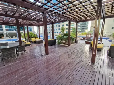a wooden deck with chairs and tables on a building at Spacious Master Bedroom with Balcony Horizon Tower, Dubai Marina in Dubai