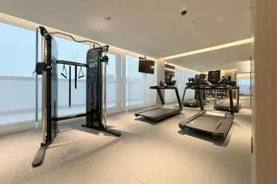 a gym with cardio equipment in a room with windows at Cosy Sobha Hartland Apt - Pool&Gym - Near Downtown in Dubai