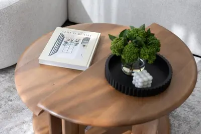 a table with a book and a vase with a plant on it at Cosy Sobha Hartland Apt - Pool&Gym - Near Downtown in Dubai
