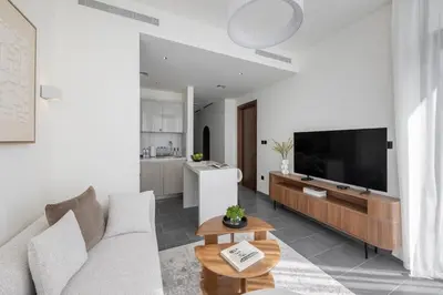 a living room with a couch and a flat screen tv at Cosy Sobha Hartland Apt - Pool&Gym - Near Downtown in Dubai