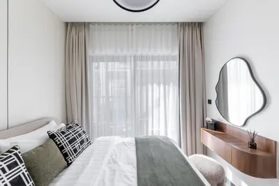 a bedroom with a bed and a mirror and a window at Cosy Sobha Hartland Apt - Pool&Gym - Near Downtown in Dubai