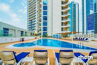 a swimming pool with chaise lounges and chairs next to buildings at New 2BR in Dubai Marina - JBR & Marina View in Dubai