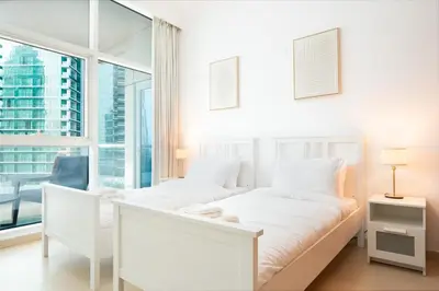 a white bedroom with a bed and a large window at New 2BR in Dubai Marina - JBR & Marina View in Dubai