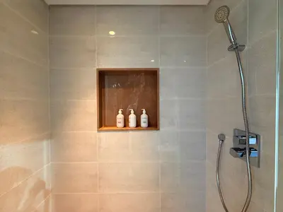 a bathroom with a shower with three bottles on a shelf at Urban Luxury Burj Vista Apartments Direct Burj Khalifa View in Dubai