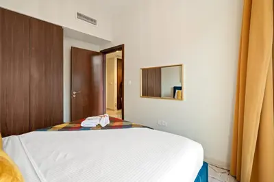 a bedroom with a white bed and a mirror at Fireworks Burj Khalifa View - One bedroom Apartment in Dubai