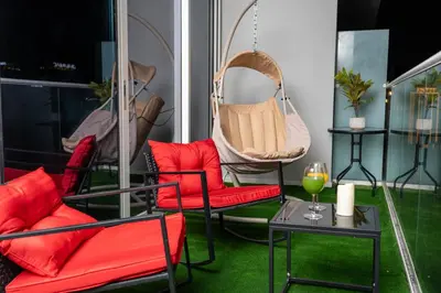 a room with red chairs and a swing and a table at Fireworks Burj Khalifa View - One bedroom Apartment in Dubai