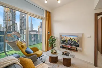 a living room with a tv and a large window at Fireworks Burj Khalifa View - One bedroom Apartment in Dubai