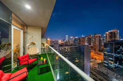 a balcony with red chairs and a view of a city at Fireworks Burj Khalifa View - One bedroom Apartment in Dubai