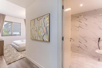 a white bathroom with a painting on the wall at HAVN - 3 Bedroom in Downtown, Burj Khalifa View in Dubai