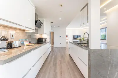 a kitchen with white cabinets and wooden floors at HAVN - 3 Bedroom in Downtown, Burj Khalifa View in Dubai