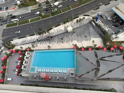 a building with a swimming pool next to a highway at MAG 318 Luxury Studio Resort Style Amenities in Dubai