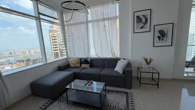 a living room with a couch and a large window at Stunning 1-Bedroom Apartment in Botanica Tower in Dubai