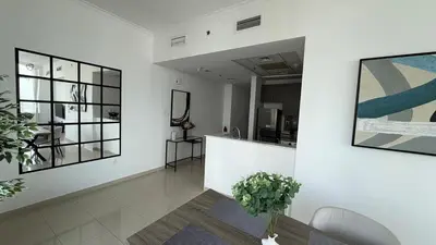 a living room with a white wall with paintings at Stunning 1-Bedroom Apartment in Botanica Tower in Dubai