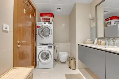 a bathroom with a washing machine and a toilet at Waves - Grand Palm Escape - Sea-View Massive 1BR Luxury in Dubai