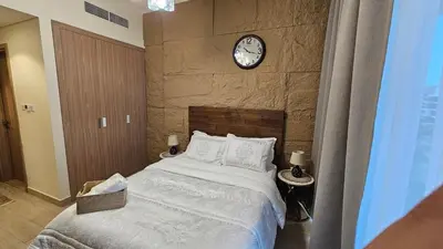 a bedroom with a bed with a clock on the wall at Luxury Studio in the Heart of Meydan in Dubai