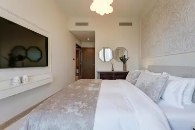 a bedroom with a large white bed and a tv at Ultra-Luxury 2BR with Burj Khalifa view Downtown in Dubai